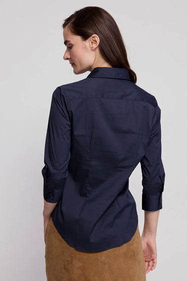 Woman wearing a navy blue shirt with rolled-up sleeves against a light gray background