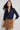 Woman wearing a navy shirt and brown skirt on a white background