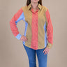 Person wearing a colorful shirt with a beige vest over a red and blue striped shirt, on a beige background.