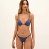 Woman wearing a blue bikini set on a beige background