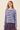 A woman wearing a light blue ribbed knit sweater with horizontal navy and red stripes, paired with a matching striped skirt, against a solid beige background.