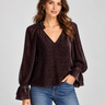 A textured black dot sheer chocolate blouse with blousy sleeves and blue jeans.