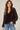 A textured black dot sheer chocolate blouse with blousy sleeves and blue jeans.