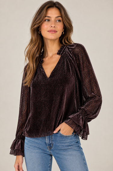 A textured black dot sheer chocolate blouse with blousy sleeves and blue jeans.