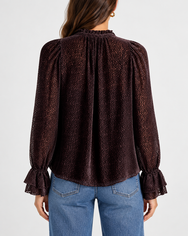 A textured black dot sheer chocolate blouse with blousy sleeves and blue jeans.