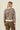 A woman shown from the back wearing a fuzzy knit sweater with a beige, brown, and black leopard print pattern, paired with olive green pants, against a solid light beige background.