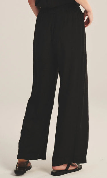 Person wearing black wide-leg pants on a beige background