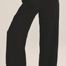 Person wearing black wide-leg pants on a plain background