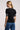 a woman wearing a black blouse with smocked puff sleeves and jeans on a neutral background