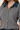 A close-up of a woman wearing a gray cable-knit short-sleeve button-up top with a dark blue denim collar and gold-tone buttons.