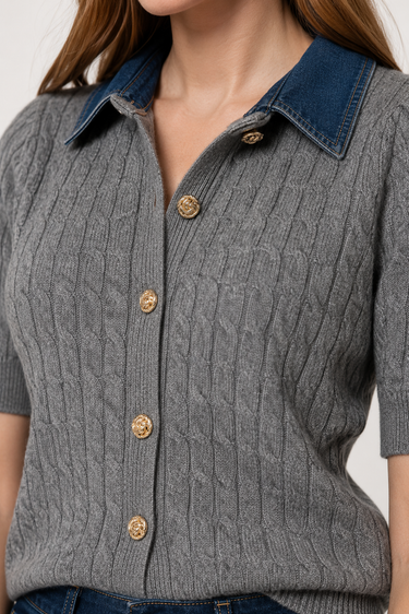 A close-up of a woman wearing a gray cable-knit short-sleeve button-up top with a dark blue denim collar and gold-tone buttons.