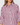 A close-up of a woman wearing a long-sleeve button-front shirt with vertical burgundy and white stripes, a pointed collar, and a chest pocket.