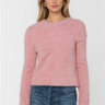 A woman modeling a fuzzy, long-sleeve crewneck sweater in dusty pink, paired with blue jeans, against a plain light gray background.