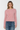 A woman modeling a fuzzy, long-sleeve crewneck sweater in dusty pink, paired with blue jeans, against a plain light gray background.