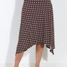 A brown and white polka dot wrap midi skirt worn by a model, shown from the waist down against a white wall.