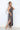 Woman wearing a patterned dress with a slit on a white background