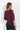 Plum off-the-shoulder three-quarter sleeve top with a relaxed draped fit, styled with dark wash jeans on a model.