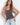 A woman modeling a brown camisole top with white polka dots and light blue jeans against a white studio background.