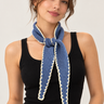 a woman wearing a cashmere knit scarf in Baltic blue with off white stitching.