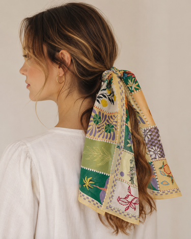 A woman wearing a patchwork scarf around her ponytail 