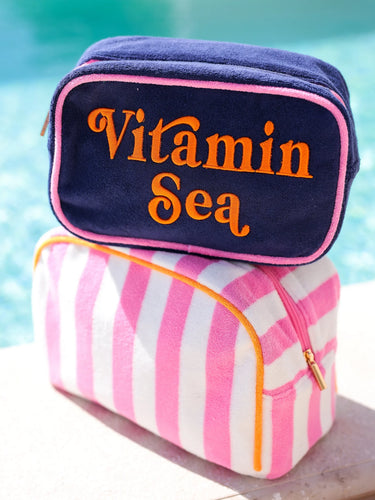 Two bags stacked on a surface with 'Vitamin Sea' text against a blurred pool background