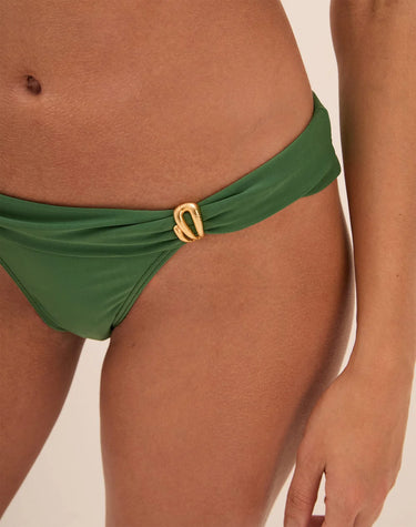 Green bikini bottom with a gold buckle on a beige background