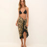 Woman wearing a black bikini top and leopard print sarong on a white background