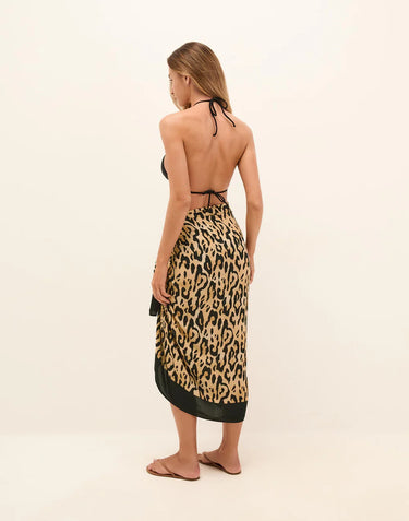 Woman wearing a leopard print sarong with a plain background