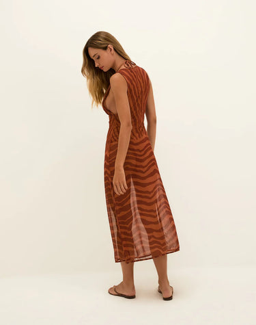 Woman wearing a rust-colored dress with a subtle pattern on a white background