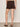 A woman wearing mid rise rich brown shorts on a neutral background