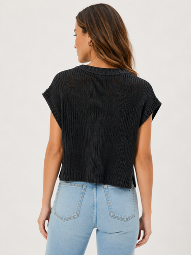 A woman shown from the back wearing a black ribbed short-sleeve knit top and light blue jeans against a plain light gray studio background.
