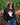 A woman wearing a black knit sweater with a ghost wearing orange heart sunglasses