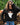 A woman wearing a black knit sweater with a ghost wearing orange heart sunglasses