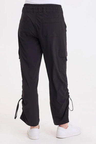 A woman wearing black cargo pants with a cinched detailing on the side of the leg panel.