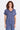 A woman wearing a blue twill v-neck short sleeve top and matching cargo pants on a white background.