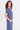 A woman wearing a blue twill v-neck short sleeve top and matching cargo pants on a white background.