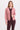 a woman wearing a pink corduroy jacket and berry pants on a white background.