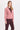 a woman wearing a pink corduroy jacket and berry pants on a white background.