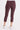 A back angle of a woman wearing leggings with a drawstring waist with zippered mini pockets team up with ruched front leg panels, front/back pockets and a cropped silhouette.