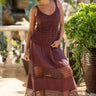 Woman wearing a brown dress with lace details standing outdoors.