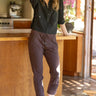 A woman wearing a black active jacket and berry pants on a whit background