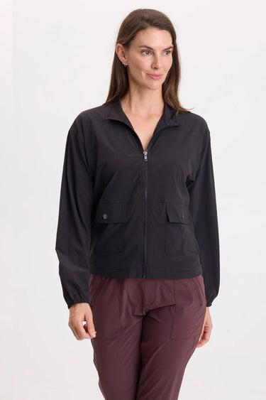 A woman wearing a black active jacket and berry pants on a whit background