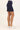 Person wearing a navy blue skirt with white sneakers on a light background