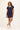 Woman wearing a navy blue skirt and shirt with a plain background