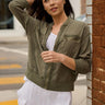 A woman wearing a white outfit with a moss green cargo jacket