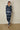 Person wearing a blue tie-dye outfit standing against a plain background