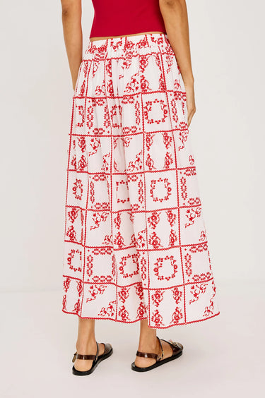 Person wearing a red and white patterned skirt on a plain background