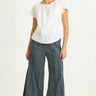 Woman wearing a white blouse and gray wide-leg pants on a white background
