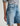 Person wearing a striped shirt and denim shorts on a plain background
