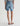 Person wearing blue denim shorts with a brand patch on a neutral background